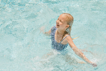 Pretty little girl in swimming pool, summer vacations.