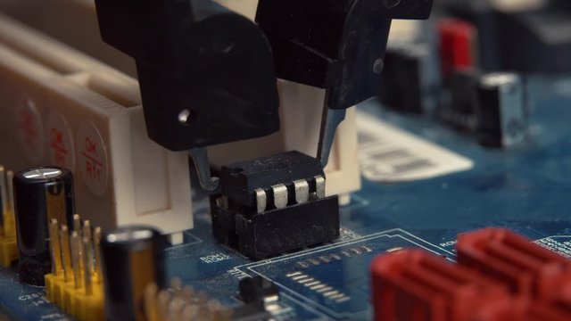 An engineer removes the programmable BIOS chip with the tongs from the motherboard. Firmware.
