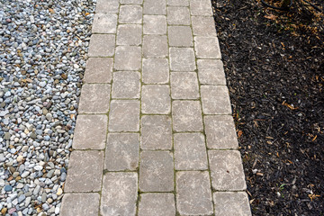 Tumbled paver walkway with wood chip and pea gravel mulches create a low maintenance landscaping...