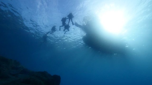 underwater scenery of scuba divers with boat end or begining of dive 