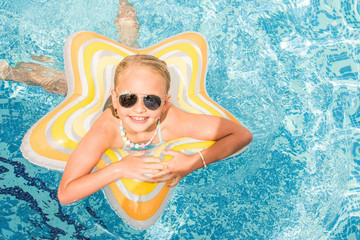 Pretty little girl in swimming pool, summer vacations.
