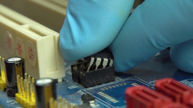 An engineer removes the programmable BIOS chip with the tongs from the motherboard. Firmware.