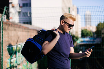 Young blond guy using a cell phone on the street