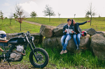 Young couple sitting looking at a map during a motorcycle trip
