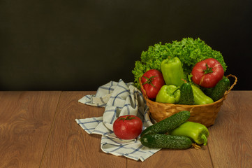 still life with vegetables in a basket on a black background with a white napkin in a blue cage