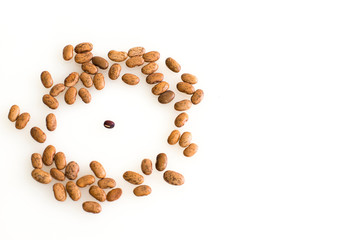 A large circle of bigger brown beans circle around a lone smaller bean in the middle, signifying bullying, bias, prejudice, prejudice, overtaking, jeering, enclosure or other intimidating act. 