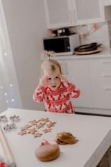 Little girl 2 years old sitting in the kitchen in red pajamas, messing with flour, baking...