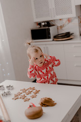 Little girl 2 years old sitting in the kitchen in red pajamas, messing with flour, baking...