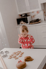 Little girl 2 years old sitting in the kitchen in red pajamas, messing with flour, baking...