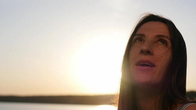 Portrait of a young woman wearing protective mask on a sunset background. Female model takes off the mask. Covid -19.