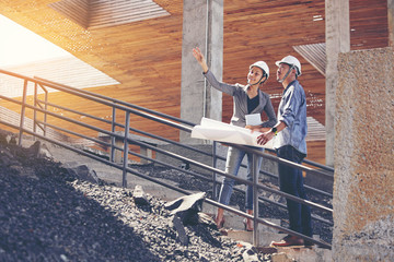 Two engineers work on the construction site. They are checking the progress of the work..