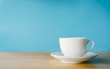 cup of coffee on wooden table with blue background 