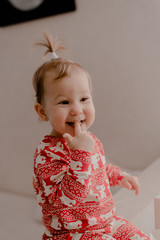 Little girl 2 years old sitting in the kitchen in red pajamas, messing with flour, baking...