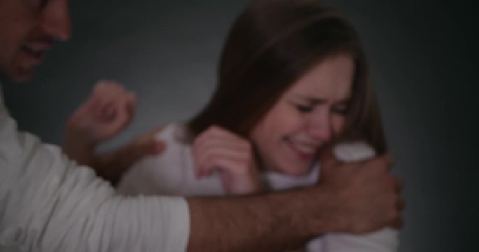 Blurred view of man shaking his girlfriend on grey background. Domestic violence