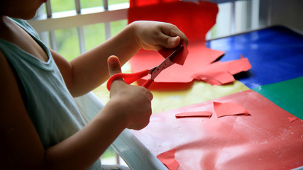 salvador, bahia / brazil - may 18, 2020: child is seen using scissors to cut paper during school assignment.