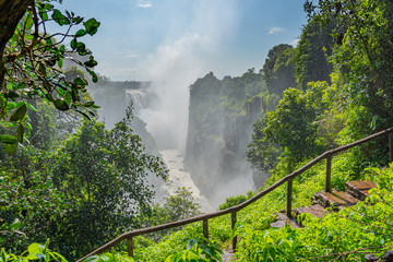 Victoria Falls on Zambezi River, border of Zambia and Zimbabwe with a walking way and rain forest