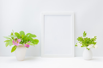 Home interior with decor elements. Mockup with a white frame and small flowers and green leaves in a vase on a light background
