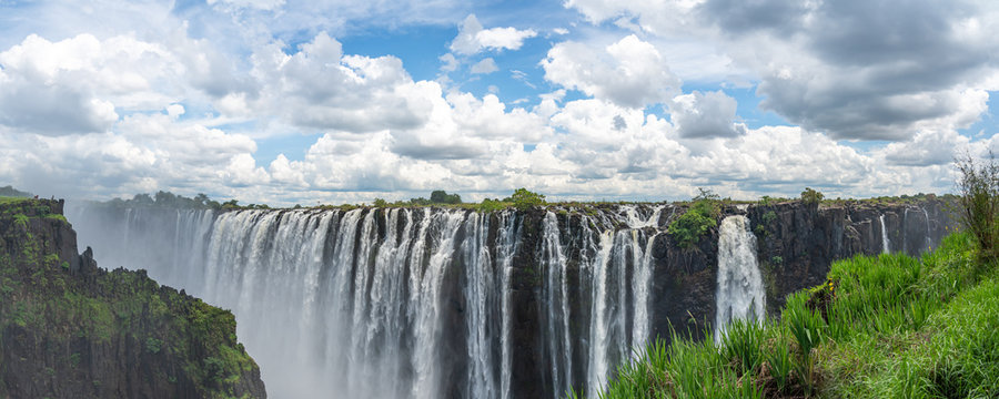 Panorama view of Victoria Falls of Zambezi River, border of Zambia and Zimbabwe with blue sky and dramatic clouds