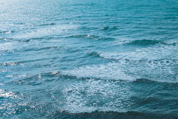 Texture of the sea or ocean with white lamb waves rolling to the shore.