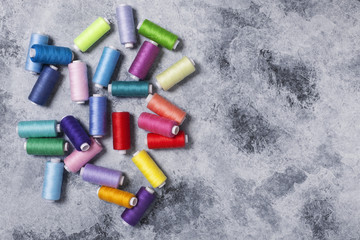 Colorful threads on bobbins, sewing set.On gray concrete background. Place for text.
