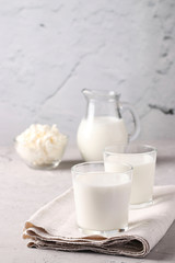 Kefir or Ayran fermented drink in two glasses, milk in jug and cottage cheese in a bowl on light gray background, Vertical format