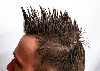 A man with a mohawk turned sideways on a white background