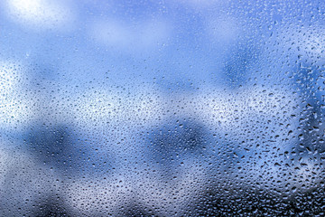 Rain drops on window glass on blue color..