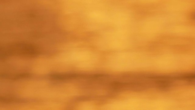 defocused shot of small ripple wave in sea, shiny sparkling sunlight reflection in water with bokeh of sun glares , blurry ocean on sunny day, abstract and blackground concept golden color
