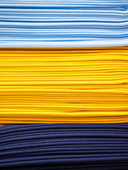 Bright yellow and blue fabric laid in layers, close-up. Background with a bright and expressive fabric texture. Assortment of multi-colored fabrics in the store