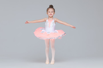 Cute adorable ballerina little girl in pink tutu dance practices ballet dancing