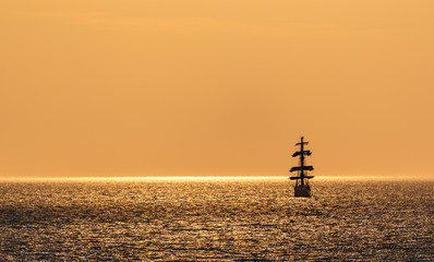Seascape with sailing ship on sunset. Silhouette of sailing vessel floating in the sea. Copy space....