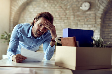 Displeased businessman reading a document after being fired in the office.