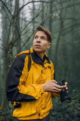 Young man photographer exploring foggy forest.