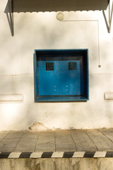 Closed square double-window window for the delivery of goods in the warehouse. Blue metal window with bars, electric bell on the wall 