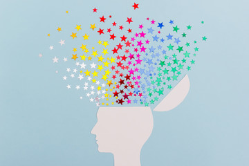 Сardboard silhouette of a human head and colorful stars confetti on a blue background. Human Mind...