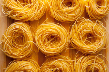 Photo of beautiful golden three pasta raw yellow nests, bio raw food