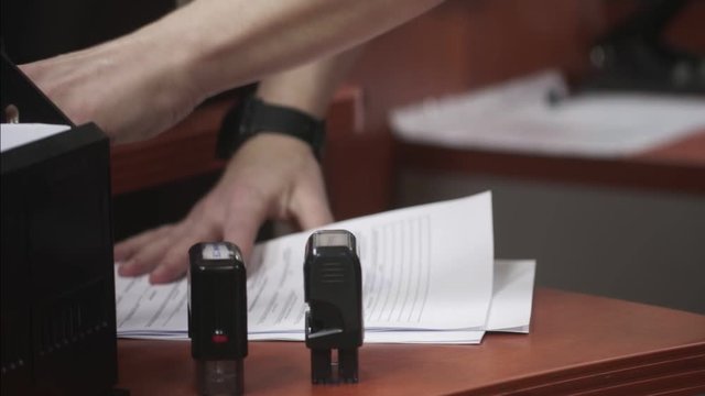 Close up of female hand that puts a stamp in the contract or documents.