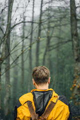 Young man photographer exploring foggy forest.