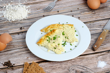 Omelette with green onion on wooden table
