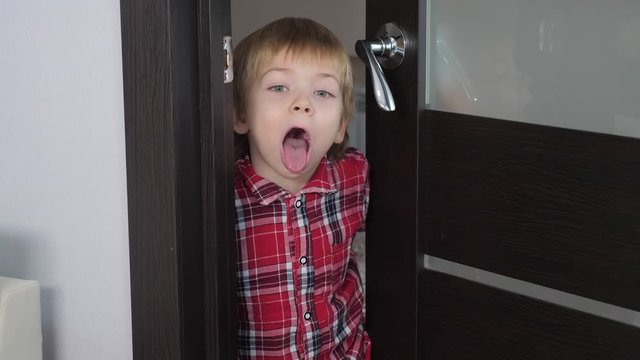 boy playing indulges concept. little boy shows tongue. the child opens lifestyle the door to indoors the room