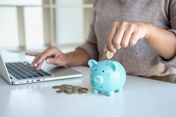 Young woman putting coins into piggy bank planning growing saving to strategy with money box for...