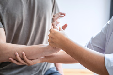 Doctor or Physiotherapist working examining treating injured arm of athlete male patient, stretching and exercise, Doing the Rehabilitation therapy pain in clinic