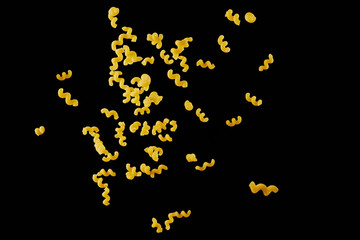 Italian flying raw pasta isolated on black background. macaroni cellentani falling.