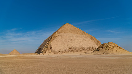 The Bent Pyramid is an ancient Egyptian pyramid located at the royal necropolis of Dahshur, approximately 40 kilometres south of Cairo, built under the Old Kingdom Pharaoh Sneferu. Egypt