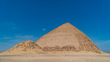 The Bent Pyramid is an ancient Egyptian pyramid located at the royal necropolis of Dahshur, approximately 40 kilometres south of Cairo, built under the Old Kingdom Pharaoh Sneferu. Egypt