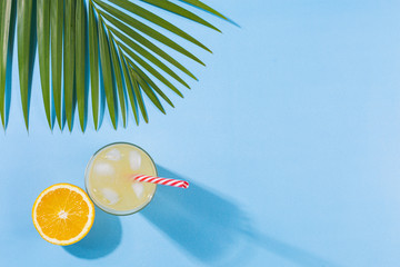 Beach accessories on a turquoise blue background - palm leaves, orange fruit, orange juice, travel postcards Summer is coming to a head. Holiday concept by the sea. Holiday accessories map in yellow