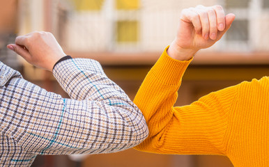 Social distancing. Two people bump elbows to avoid coronavirus outdoors. Friends demonstrating a new way of greeting during coronavirus epidemic