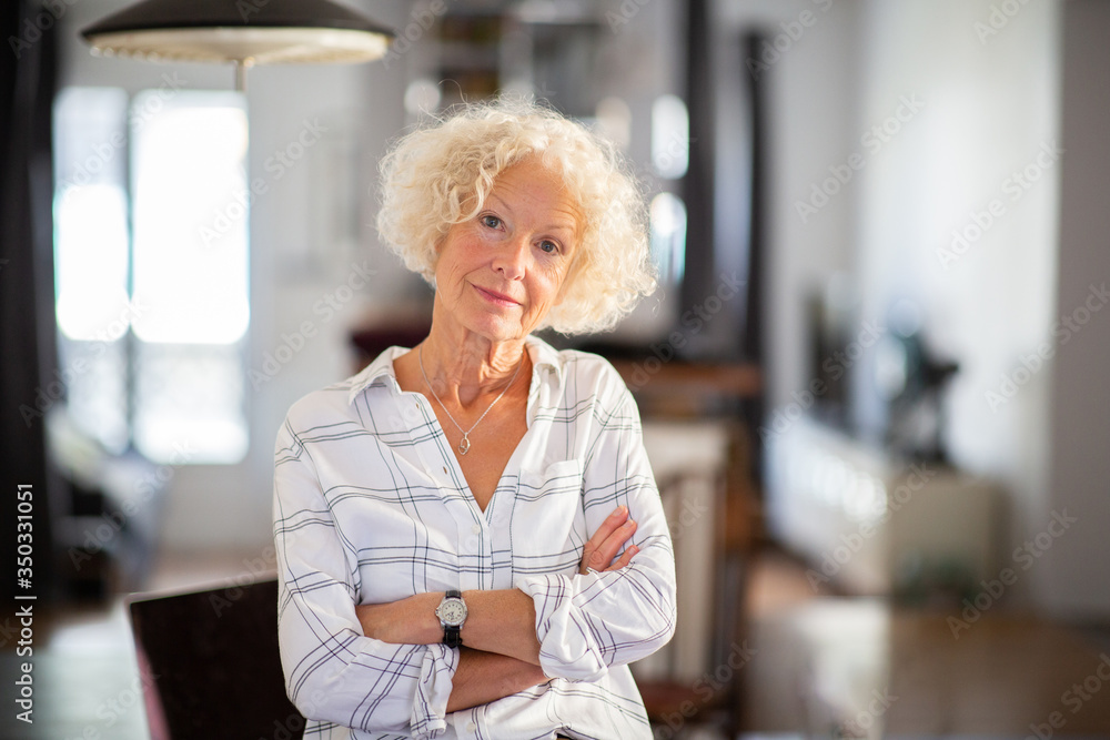 Wall mural attractive older woman with arms crossed at home