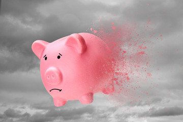 No money or savings have disappeared. Piggy bank turns into sand against the sky