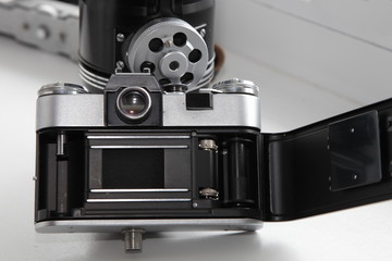 Vintage SLR camera back side with viewfinder, open cap and film drive mechanism and a shutter on retro photo equipment background